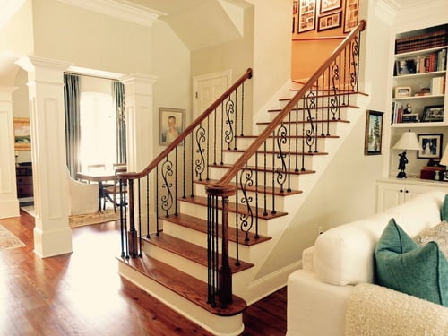 white columned living area with ornate scroll balusters going up white staircase