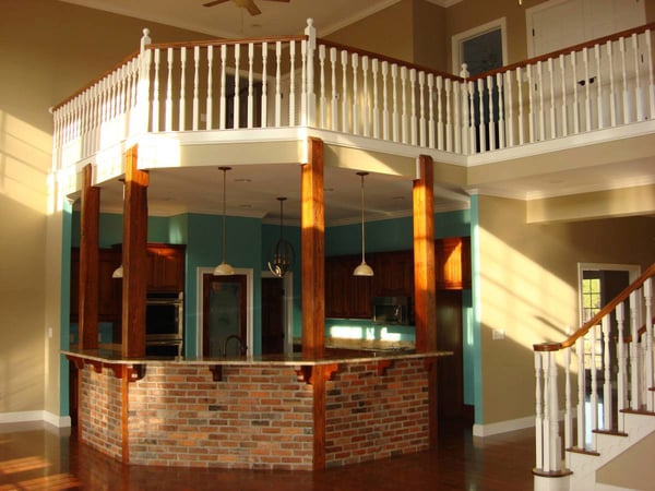 White primed balusters with wood handrail on stairs and balcony above brick kitchen